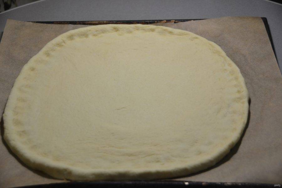 Раскатайте тесто в пласт, перенесите на противень, застеленный пекарской бумагой, сделайте небольшие бортики.