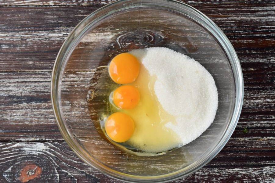 Вбейте куриные яйца в миску. К ним добавьте сахар.