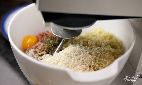 Третью часть готового лука и все остальные ингредиенты для фрикаделек (яйца, сол, перец, сыр, орегано и сам фарш) смешиваем в миске. 