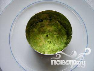 Положить кольцо в центре блюда, и положить слой авокадо на дно.
