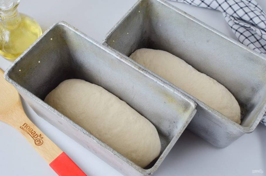 Формы для хлеба смажьте растительным маслом. Разделите тесто на две части, каждую сформируйте в виде батона, выложите в форму. Накройте полотенцем и уберите в тепло на 40 минут.