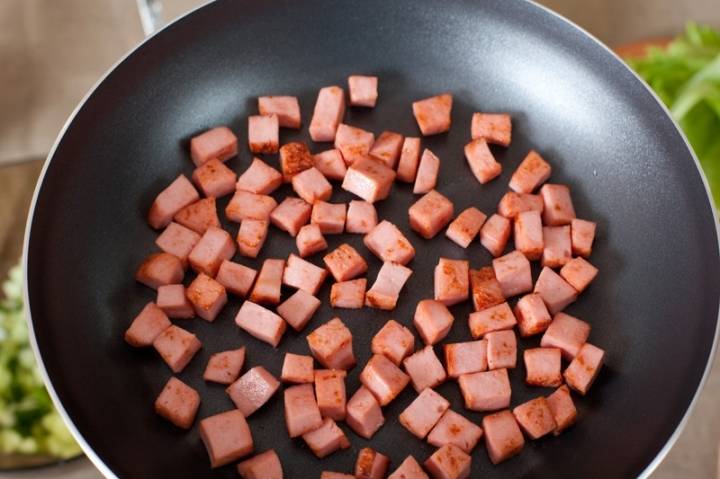 Колбаску нарезаем кубиками и обжариваем на сухой сковородке, постоянно перемешивая, до появления румяной корочки.