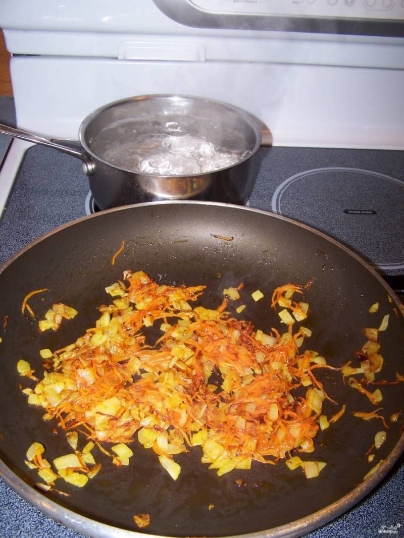 Шаг 2.
Пока мясо варится, нарежьте мелко лук и натрите на мелкой терке морковь. Лук с морковью переложите на разогретую с подсолнечным маслом сковороду. Жарьте на среднем огне до размягчения и румяности. 
Отварите яйца вкрутую (необходимо варить их около 7 минут). 