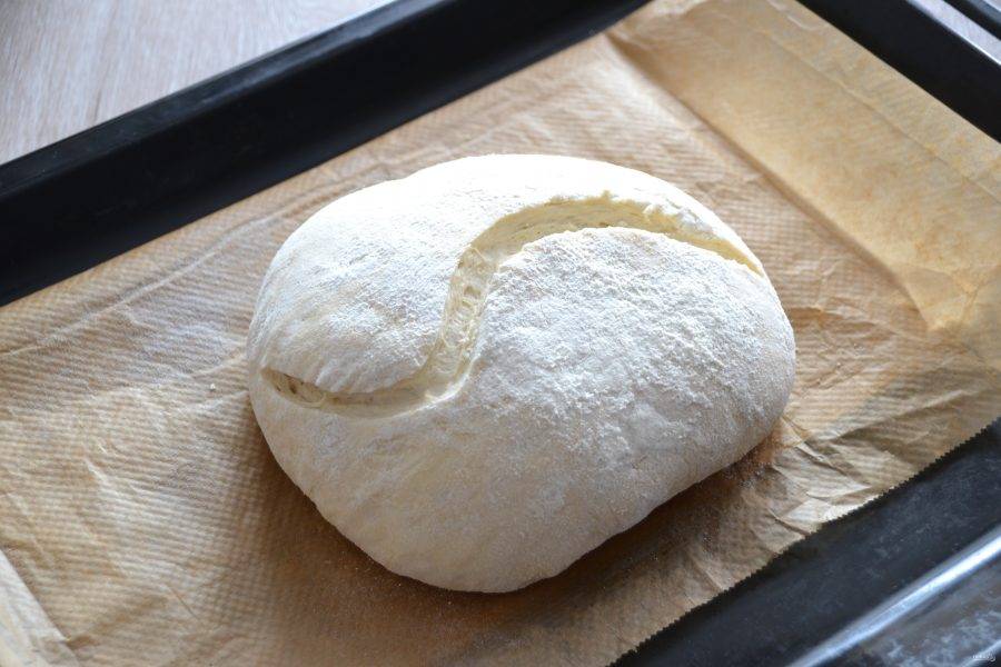 Через час переложите хлеб на противень, сделайте произвольные надрезы. Поставьте в духовку на максимальную температуру 250 градусов на 10 минут, с паром. После чего понизьте температуру до 180 градусов и выпекайте еще 40 минут.