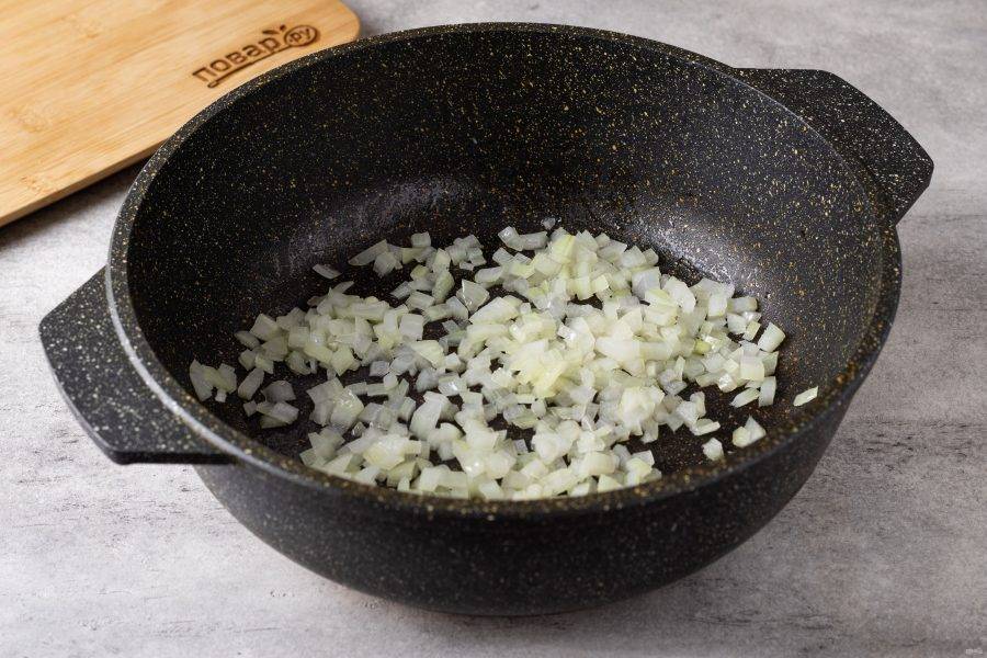 Разогрейте в сковороде растительное масло и обжарьте мелко порезанный репчатый лук до мягкости.