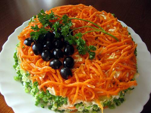 3. Теперь украшаем сверху салат оставшейся морковью по-корейски, а оливки (или маслины) нарезаем пополам и выкладываем "виноградную гроздь". Готово!