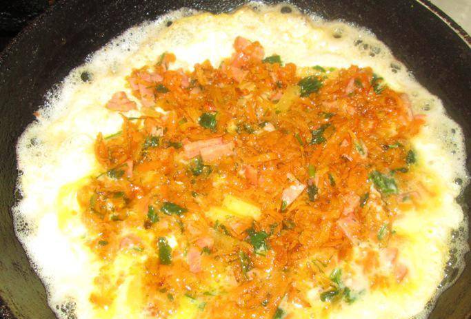 В подрумяненный омлет добавляем начинку из моркови.
