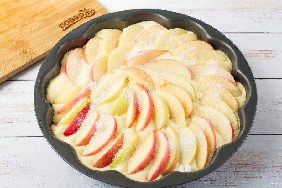 5.	Сверху распределите оставшееся тесто и красиво разложите ломтики яблок. Присыпьте сахаром.
