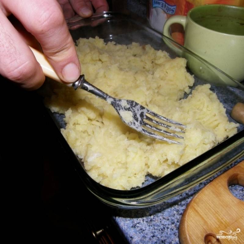 В слегка смазанную маслом форму для запекания выкладываем картофельное пюре. Разравниваем, чтобы получился ровный слой.