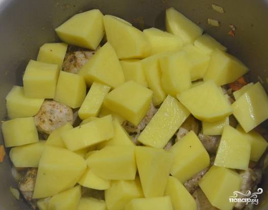 4. Начищенный картофель нарежьте кубиками средней величины. Выложите его в мультичашу. Долейте полстакана воды, если в поджарке мало влаги.