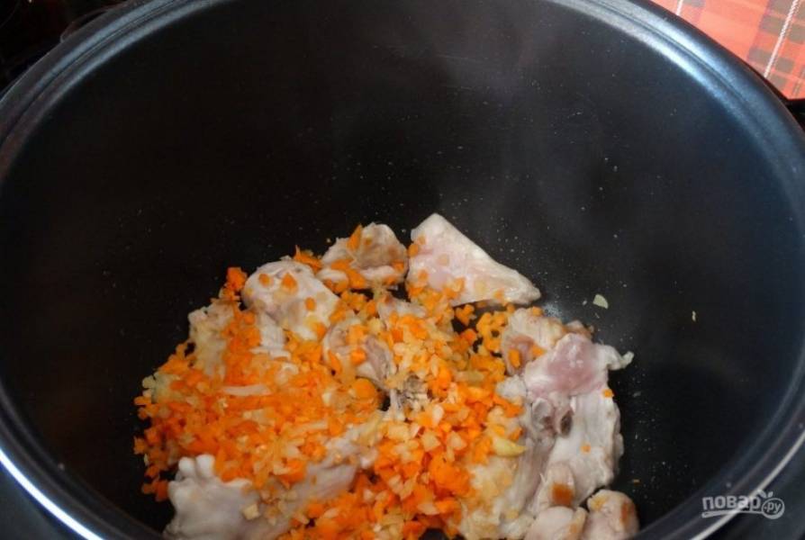 Спустя 10 минут к курице добавьте измельчённую морковь с луком. Жарьте всё вместе 5 минут.