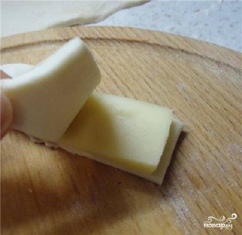 2.	Положить пластину из сыра на прямоугольник теста. Сверху на тесто положить второй кусочек теста. Защипнуть короткие края у слоечек.