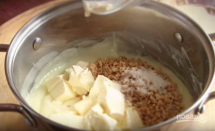 7. Варите крем на среднем огне, постоянно помешивая, до загустения. Затем добавьте орехи, ванильный сахар и сливочное масло. Взбивайте миксером 2-3 минуты. 