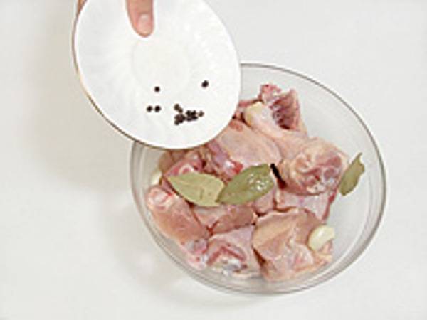 Смешайте порезанную курицу с перцем, лавровым листом и очищенным чесноком.