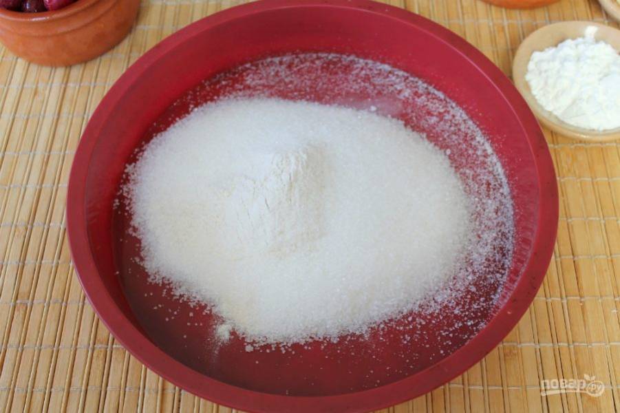 В силиконовую форму для выпечки насыпаем муку и сахар. 2 столовые ложки сахара оставляем для вишни.