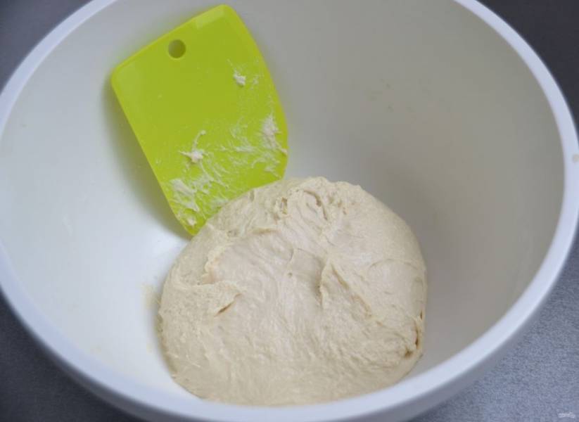 Замесите тесто. Месите руками примерно 10 минут, растягивая тесто, развивая клейковину, тесто должно стать эластичным. Соберите тесто в шар, накройте пленкой, поставьте на расстойку на 2 часа. 