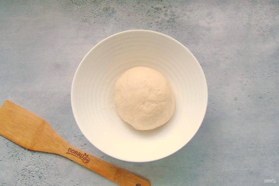 Перемешайте ингредиенты теста в миске ложкой. После выложите на поверхность, присыпанную мукой и замесите крутое, но эластичное тесто. Накройте его пленкой и дайте постоять 20 минут.