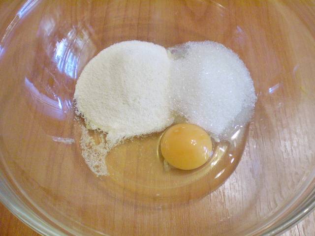 Берем удобную сухую тару: смешиваем в ней яйцо, манку и сахар.