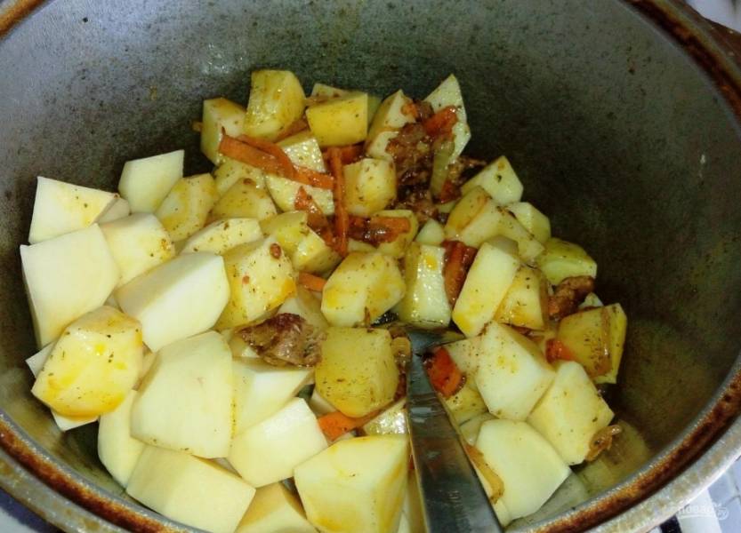 3. Тем временем чищу картошку и нарезаю ее кусочками, добавляю картошку в казан, перемешиваю. 