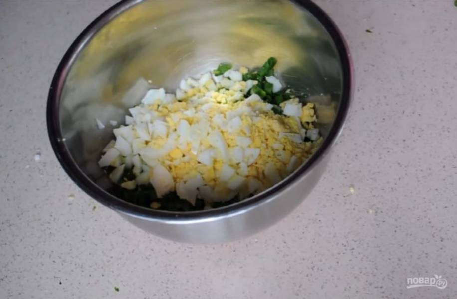 3. Мелко нарежьте зеленый лук. Заранее отваренные яйца очистите от скорлупы и мелко нарежьте. Смешайте лук и яйца, добавьте соль и перец по вкусу. Перемешайте. Начинка готова.