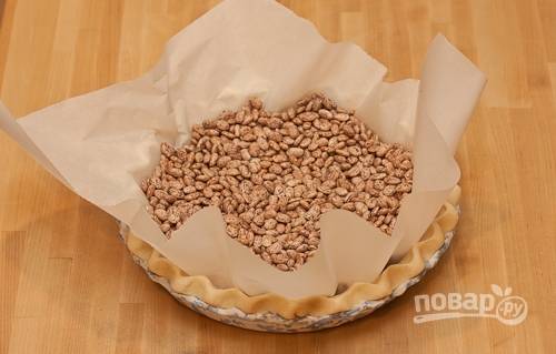 1. Выложите песочный корж в форму, накройте пергаментом и всыпьте горох или фасоль. Отправьте в разогретую до 180 градусов духовку минут на 15-20. 