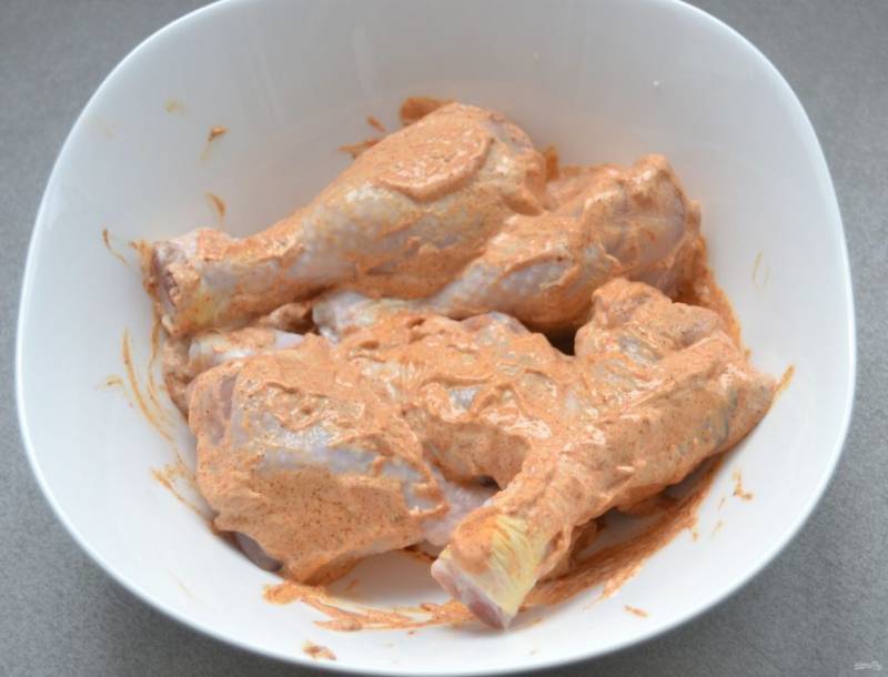 Выложите в майонезный маринад куриные голени, накройте пищевой пленкой, дайте замариноваться в течение 30-60 минут.