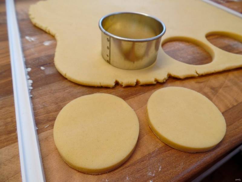 6.	Достаньте охлажденное тесто, раскатайте его в пласт около 0,8-1 см в толщину, затем круглой формочкой или стаканом вырежьте кружочки (чтобы поместились в формы для кексов).