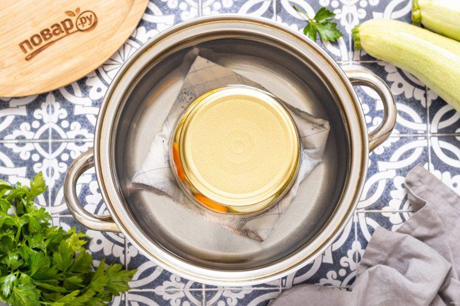 В кастрюлю постелите тряпочку или полотенце, поставьте банку и влейте воду по плечики банки. Стерилизуйте в кипящей воде 20 минут. Кабачки должны поменять цвет.