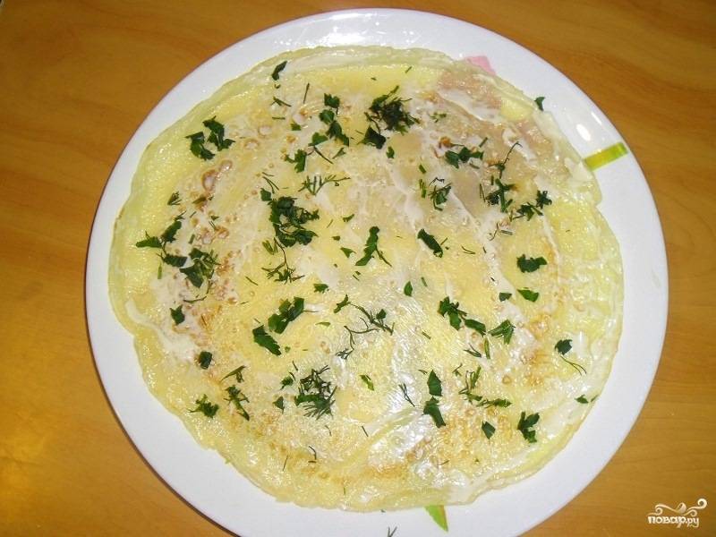 Возьмите верхний блин из стопочки и положите на отдельную тарелку. Смажьте его майонезом или плавленым сыром и присыпьте немного зеленью.