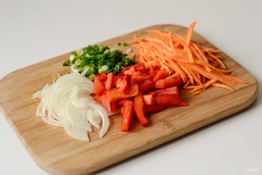 В это время подготовьте овощи. Лук нарежьте полукольцами, болгарский перец соломкой, а морковь натрите на корейской терке. Зеленый лук крупно порубите. 
