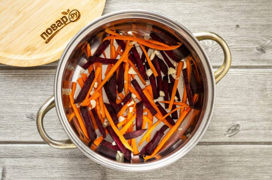 Выложите на дно глубокой кастрюли или миску часть чеснока, моркови и свеклы. Сверху выложите капусту.