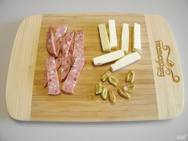 Порежьте небольшими кусочками колбасу и сыр плавленый. Оливки порежьте просто на две (или несколько) части вдоль.
