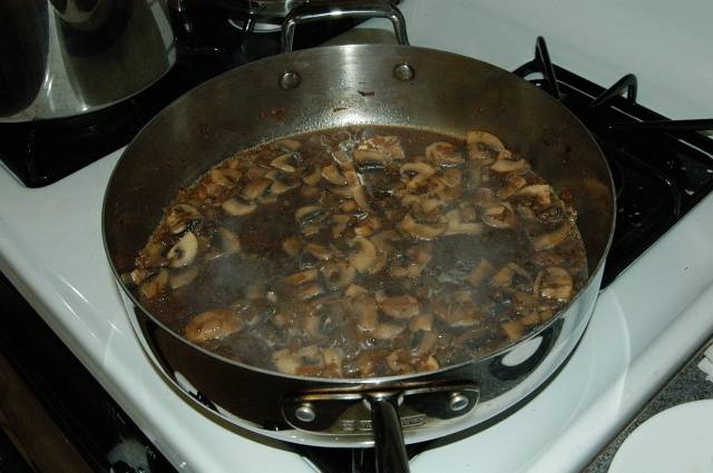 Добавьте бульон и коньяк в сковороду. Жидкость должна слегка покрыть грибочки. Тушите в течении 15 минут.
В это время можно заняться лапшой. Сварите её и добавьте 2 столовые ложки масла.