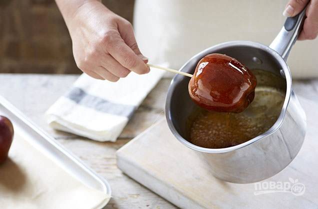 3. С помощью деревянной шпажки окуните яблоки в карамельный сироп.
