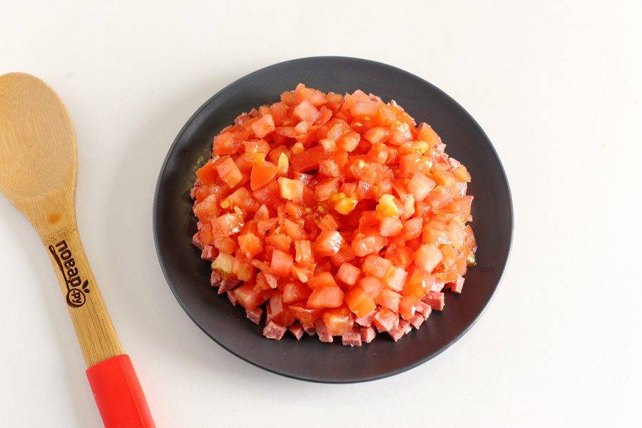 Следом выложите нарезанные примерно такими же кубиками помидоры. Если помидоры сильно сочные, то предварительно откиньте их на сито.
