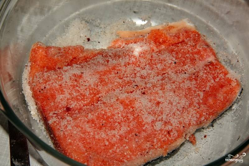 Смешайте соль, сахар и перец свежемолотый. Хорошенько натрите рыбу со всех сторон специями.
Возьмите контейнер стеклянный или пластиковый, выложите первый кусок шкуркой вниз.
