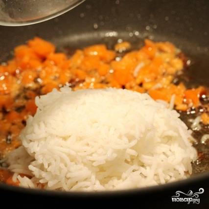 Теперь обжаренных креветок извлекаем из сковороды и перекладываем на тарелочку, а в сковороду добавляем нарезанную морковь. Спустя минуту добавляем рис.