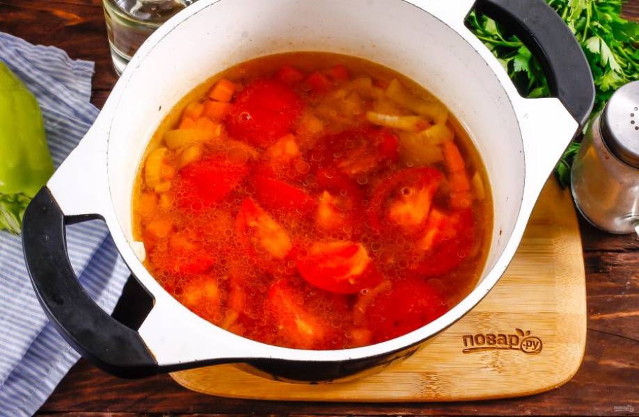 Промойте помидоры, оставляя один, и нарежьте их на четвертинки, вырезая зеленые сердцевинки. Добавьте в казан и потушите 2-3 минуты. Затем влейте горячую воду, всыпьте оставшуюся соль.