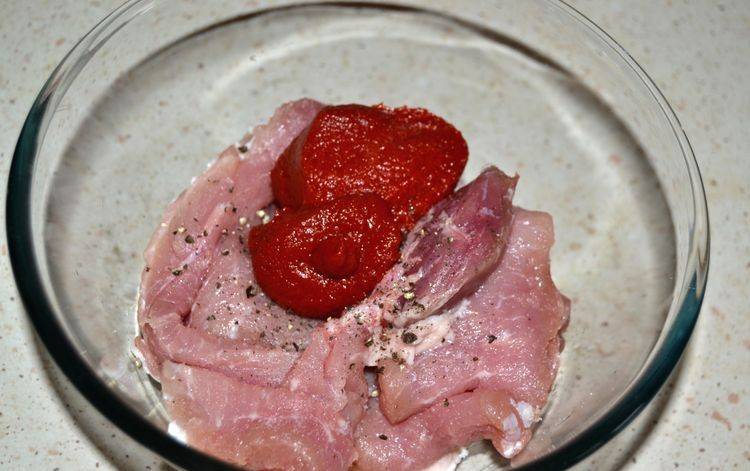 Кладем нарезанное мясо в глубокую миску, солим, перчим и добавляем томатную пасту.
