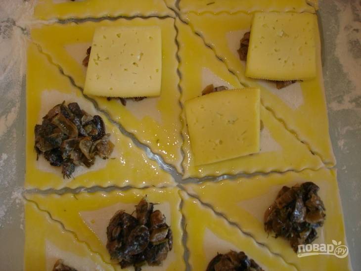 Для начинки: порежьте грибы и лук, обжарьте их до готовности на сковороде. Сыр порежьте квадратиками. 
Края треугольников смажьте желтком, разведенным с водой, чтобы те склеились. 
В центр каждого треугольника выложите грибы, сверху положите кусочек сыра.