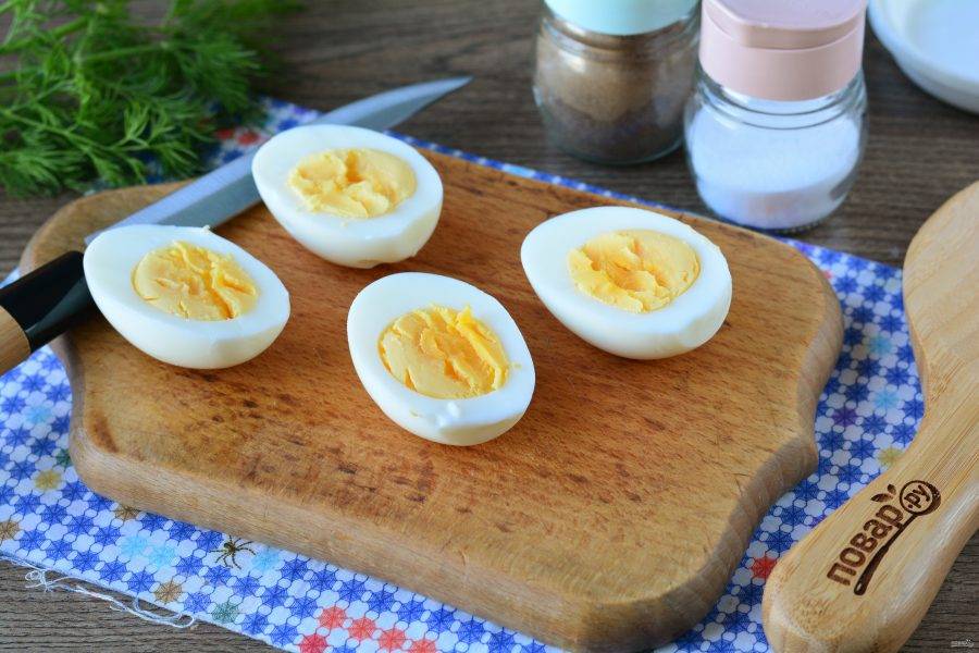 Сварите вкрутую яйца, почистите и разрежьте на равные половинки.