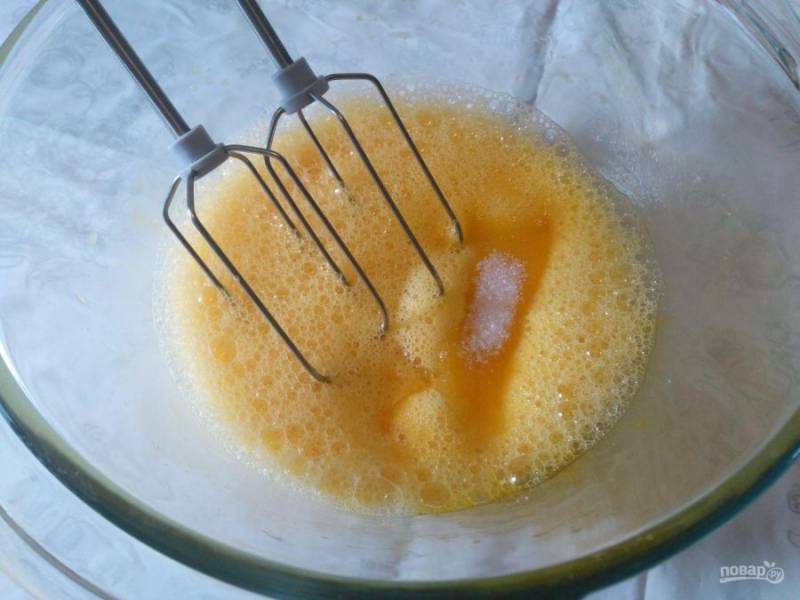Разбейте яйца в глубокую миску, добавьте щепотку соли и взбивайте миксером или венчиком, постепенно добавляя сахарный песок.