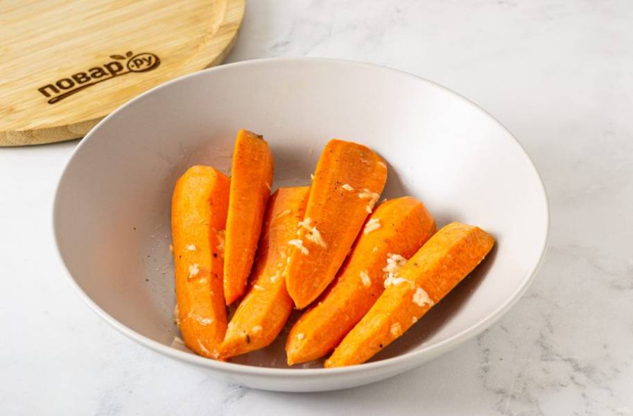 Полейте оливковым маслом морковь, добавьте тертый чеснок. Перемешайте. Посолите и поперчите по вкусу.