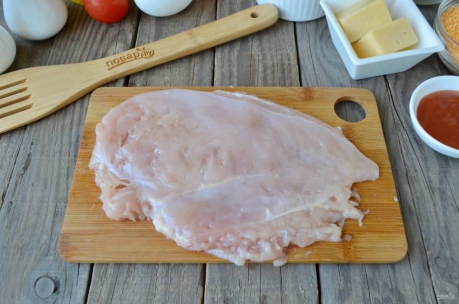 Куриное филе положите на деревянную досточку, накройте пищевой пленкой и отбейте молоточком.