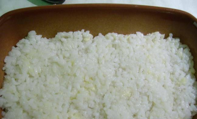 Теперь берем форму для запекания. Смазываем её маслом растительным, выкладываем часть риса с сыром. 
