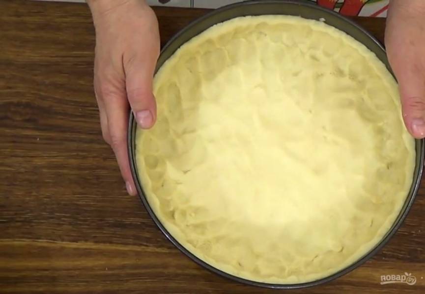 2. Форму для выпечки выстелите бумагой для выпечки и равномерно распределите тесто по дну формы, формируя бортик высотой 3-4 см. Отправьте тесто в морозилку на 20 минут. 