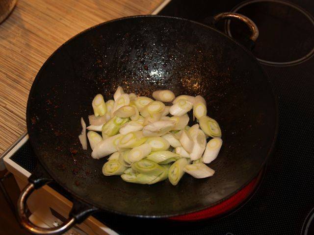 Убираем обжаренные грибы в отдельную посуду, добавляем в вок немного масла и обжариваем 1 минуту нарезанный лук-порей.
