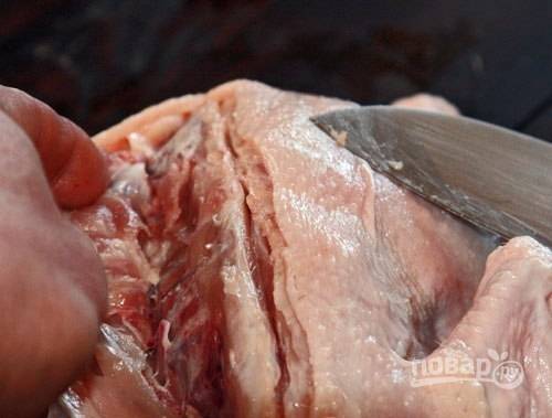 Тушку положите спинкой вверх. Надрежьте кожицу и тонкий слой мяса вдоль позвоночника. С левой стороны держите кожу, надрежьте плоть вдоль рёбер.