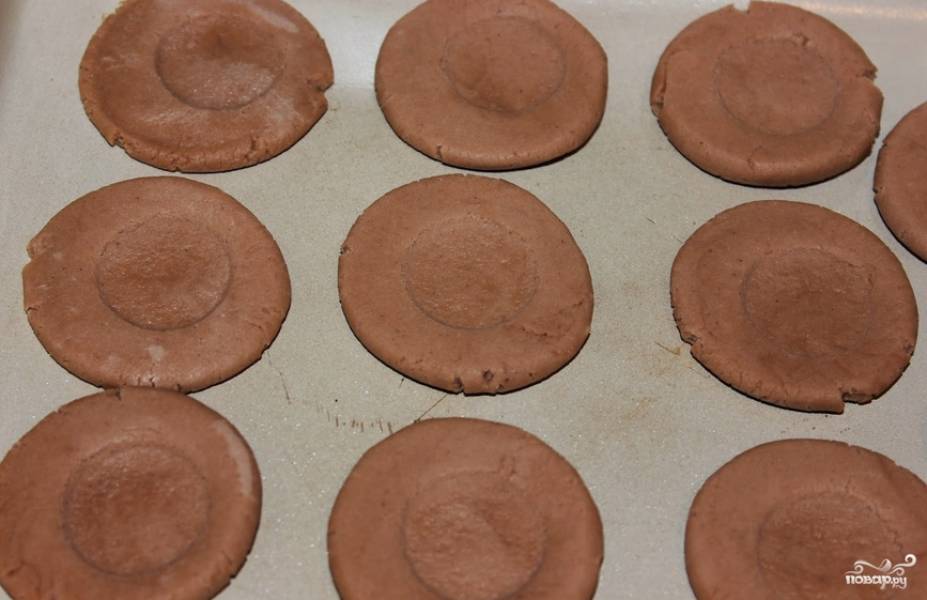 Формируем из теста круглые печеньки. По центру делаем небольшую круглую выемку (для этого процесса удобно использовать рюмочку). Выпекаем печенье в духовке до полуготовности (легкого подрумянивания). Температура — 160 градусов.
