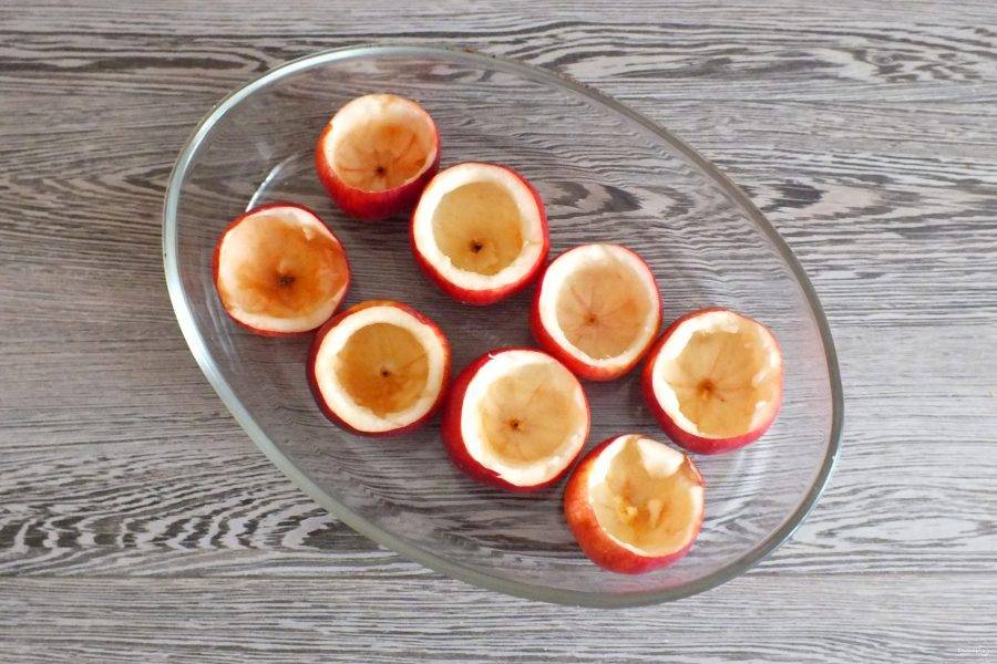 Яблоки вымойте. Срежьте верхушку. С помощью ложки или ножа удалите мякоть, оставив небольшое количество на стенках и донышке яблока. Выложите подготовленные яблоки в жаропрочную посуду.